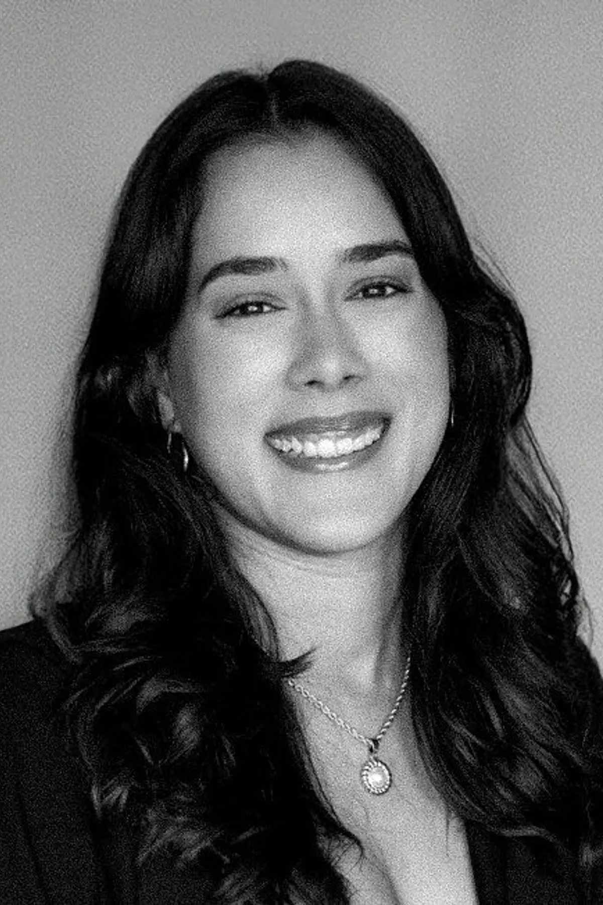 Alejandra Merced Nieves with a confident expression, wearing professional attire, photographed from the shoulders up in a minimalist studio setting.