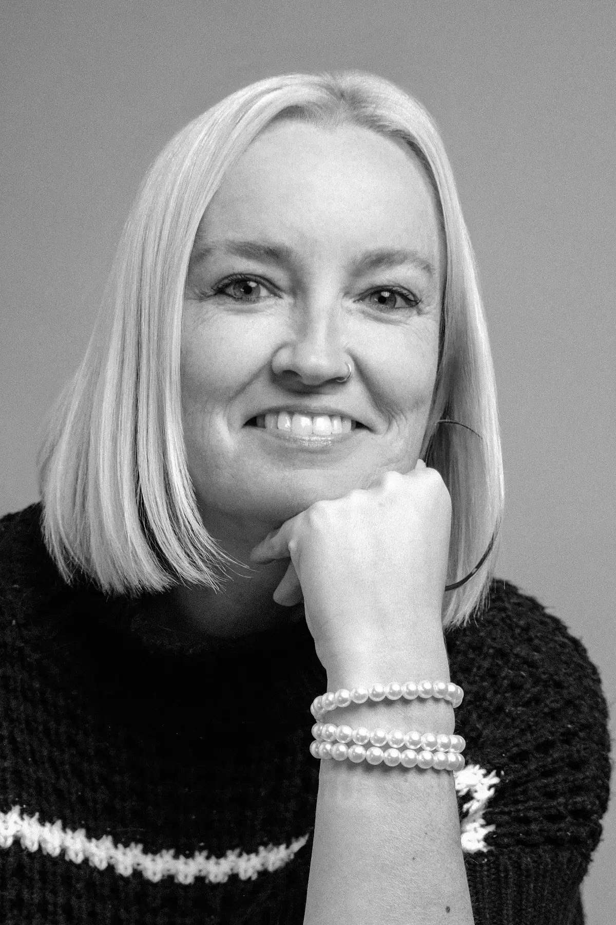 Amanda Rock with a confident expression, wearing professional attire, photographed from the shoulders up in a minimalist studio setting.
