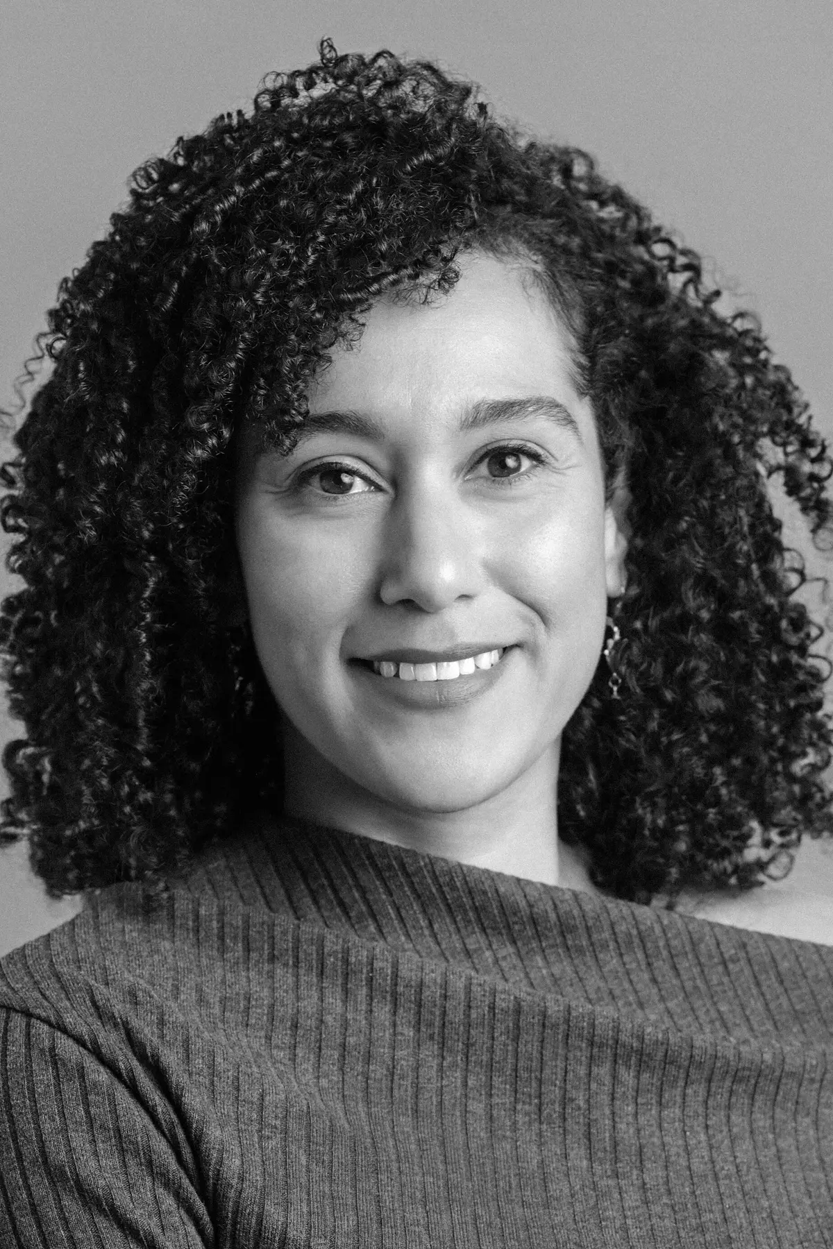 Ashley Stokes with a confident expression, wearing professional attire, photographed from the shoulders up in a minimalist studio setting.