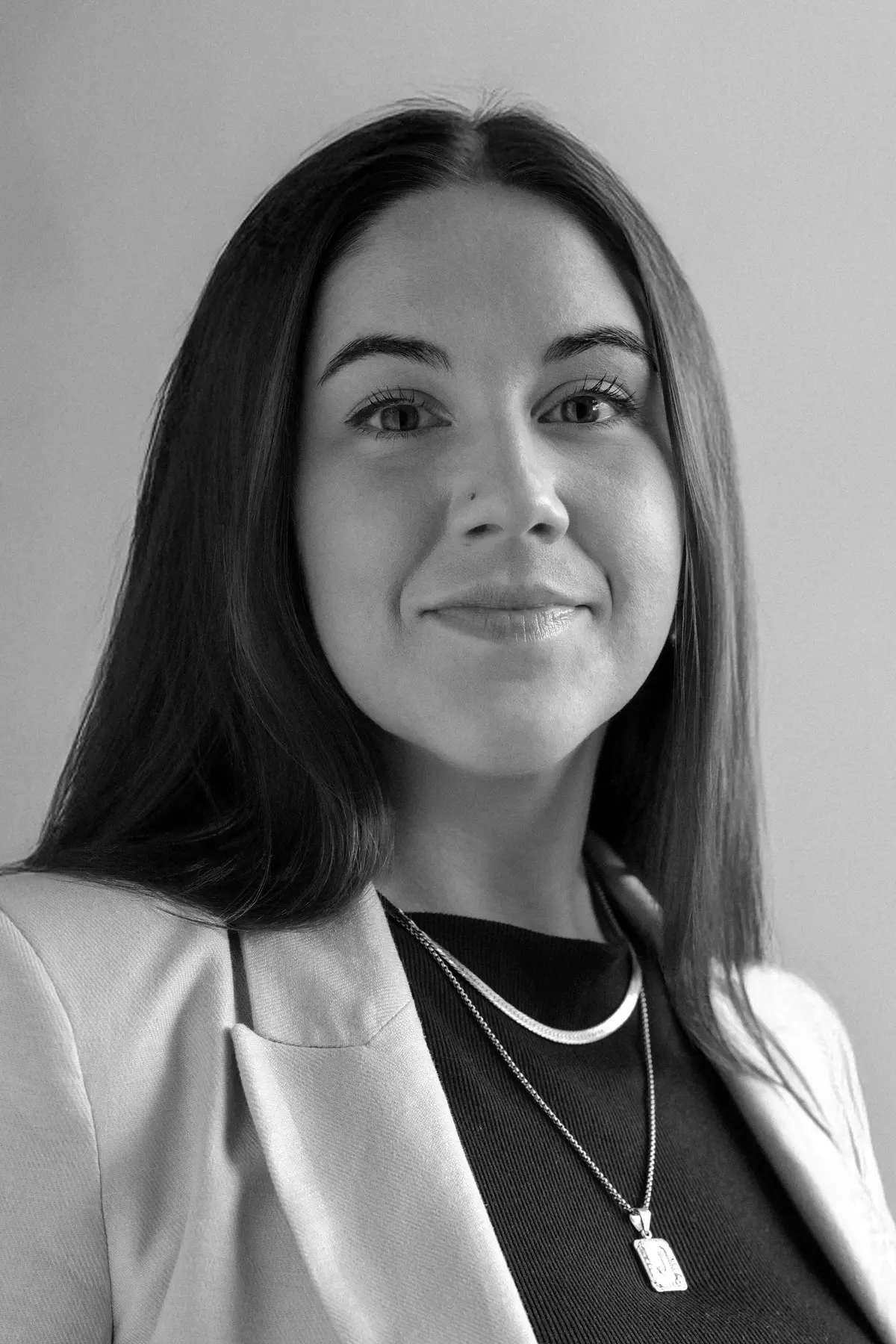 Juliana Walsh with a confident expression, wearing professional attire, photographed from the shoulders up in a minimalist studio setting.