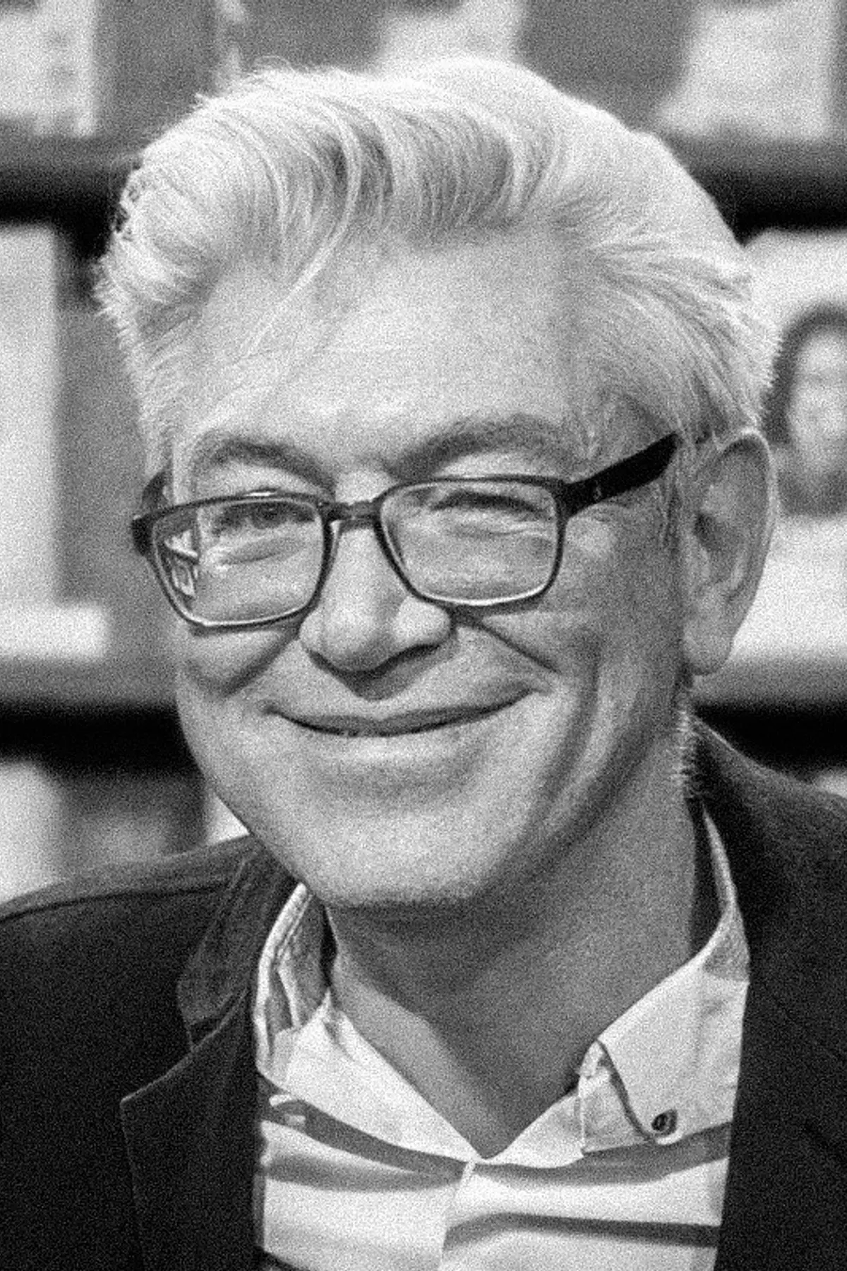 David Drake with a confident expression, wearing professional attire, photographed from the shoulders up in a book store setting.