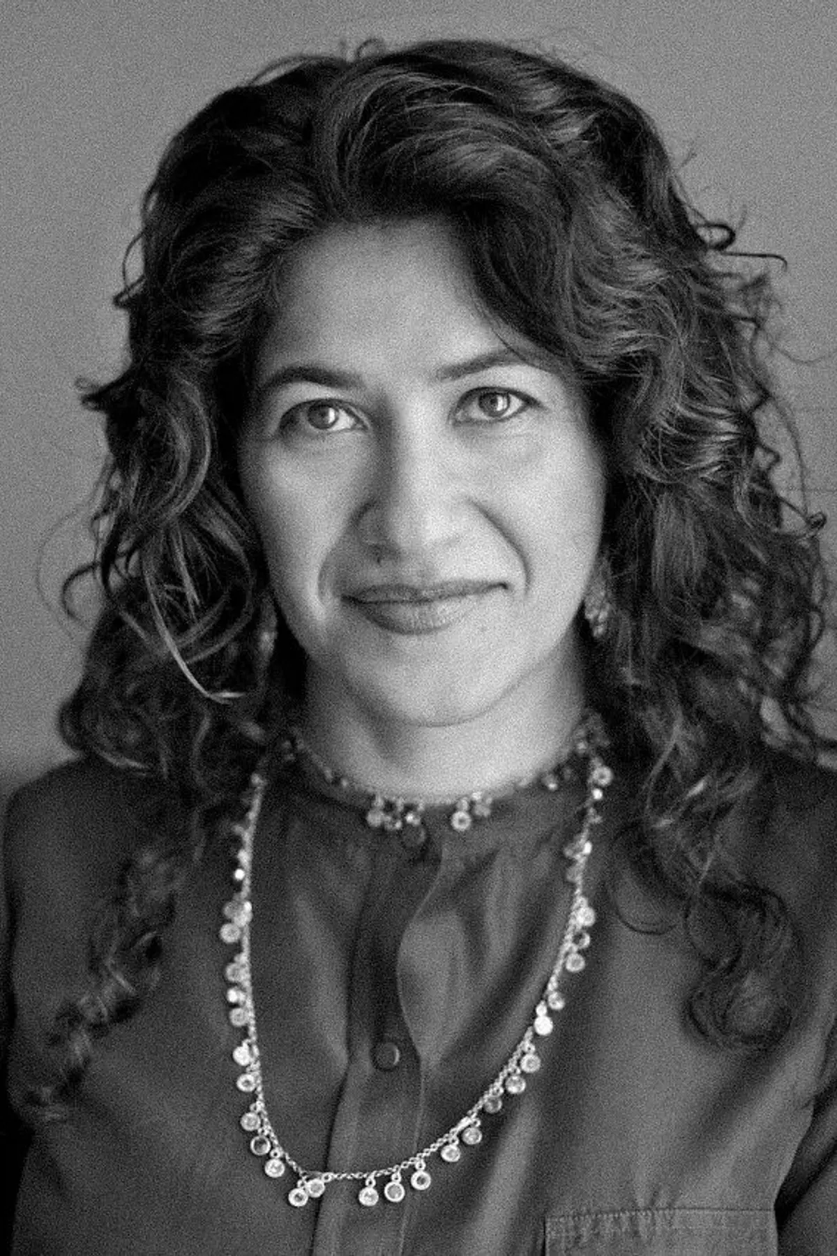 Laleh Mehran with a confident expression, wearing professional attire, photographed from the shoulders up in a minimalist studio setting.