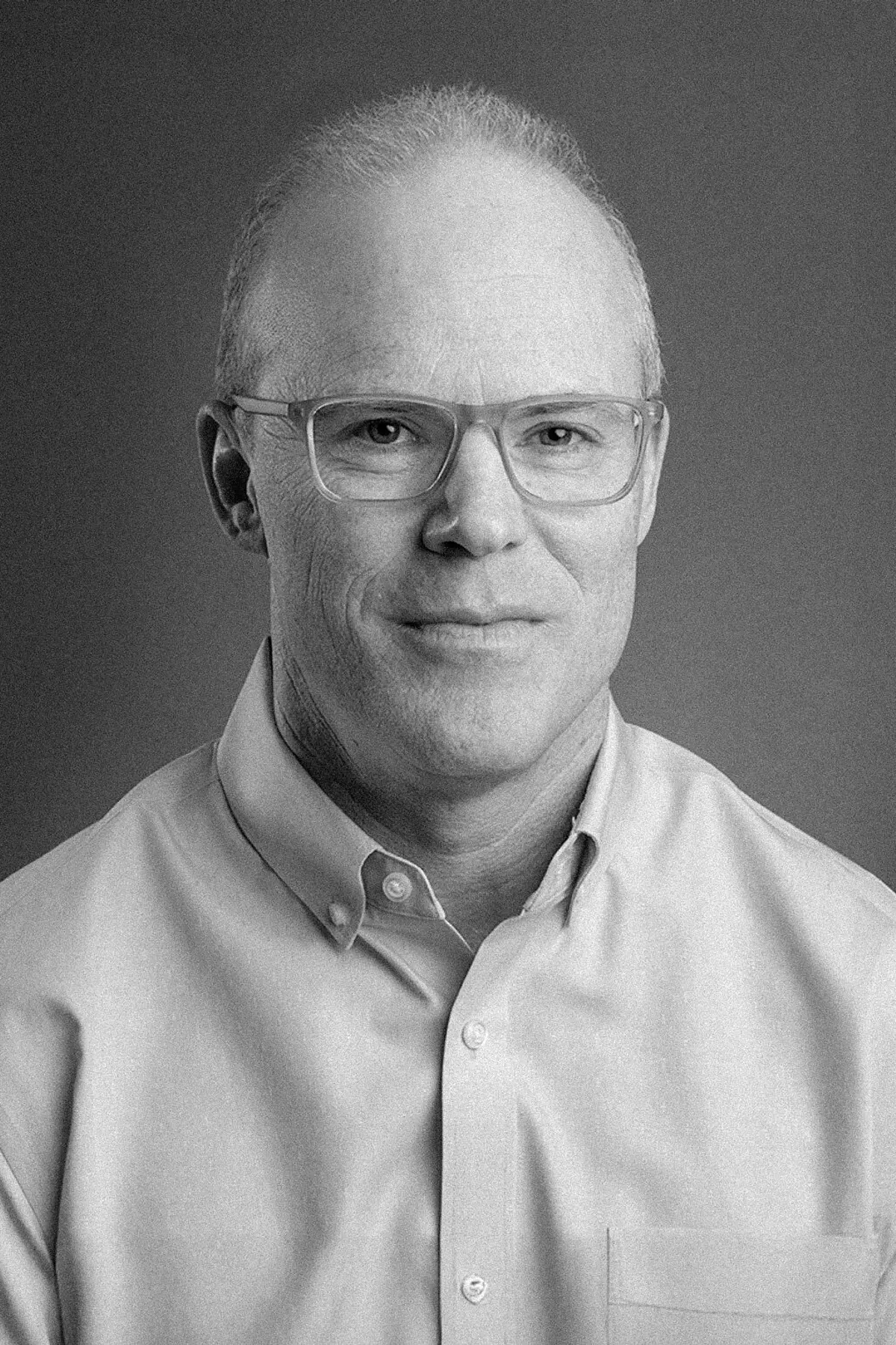 Roni Zeiger with a confident expression, wearing professional attire, photographed from the shoulders up in a minimalist studio setting.